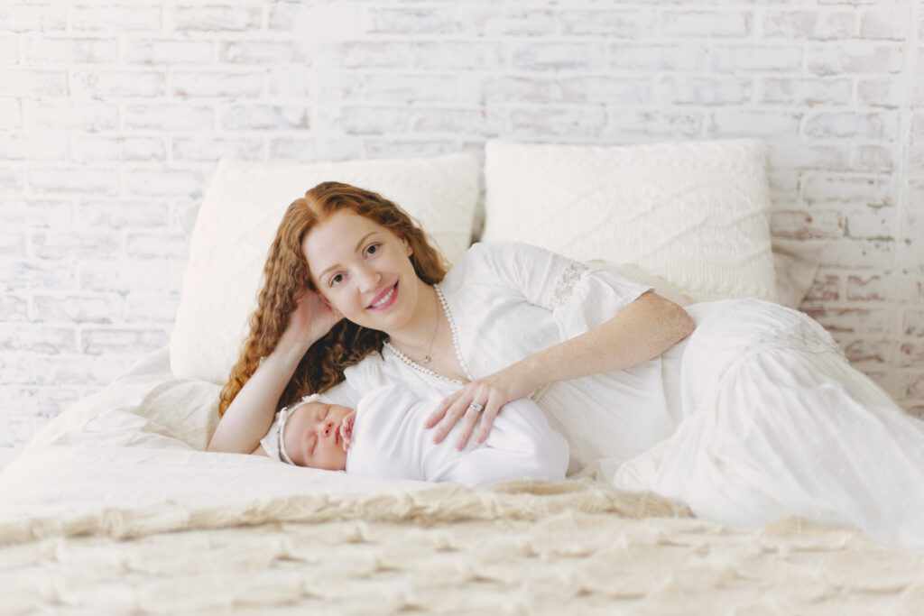 mother posing with her newborn on a bed