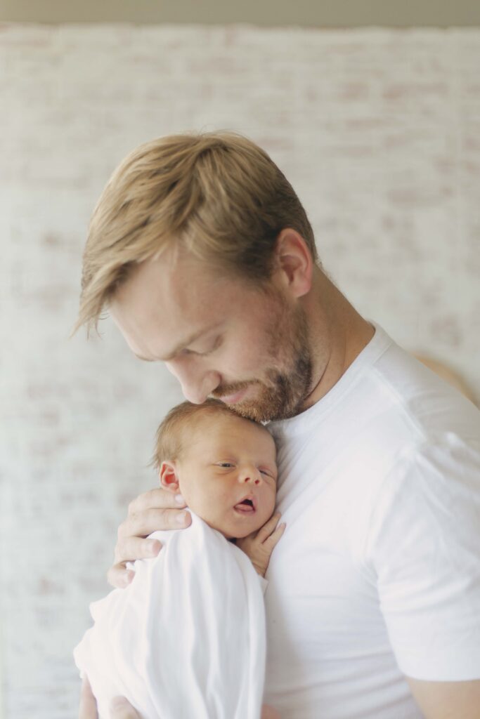 dad snuggling newborn baby