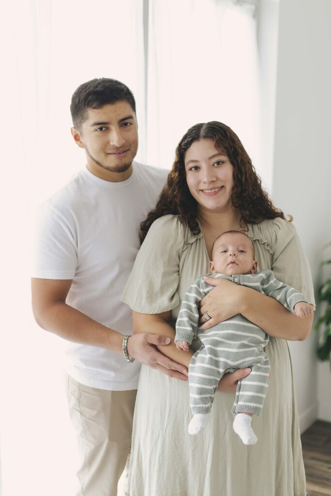 mom and dad posing for newborn photos with baby