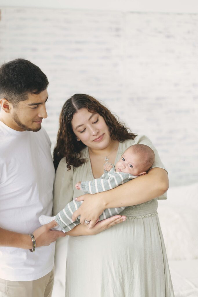 mom and dad posing for newborn photos with baby