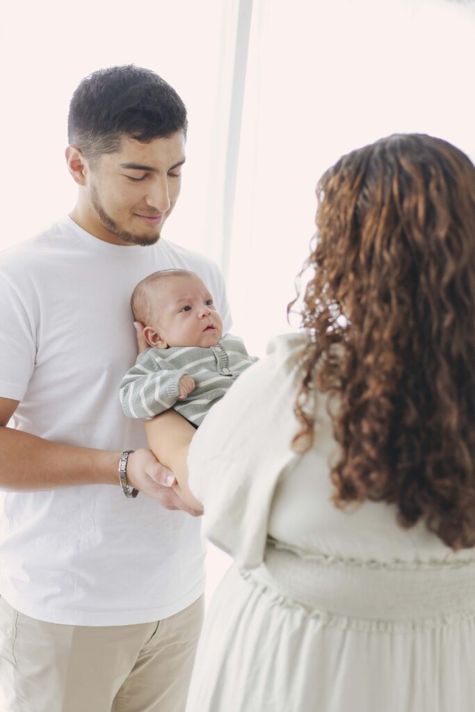 mom and dad posing for newborn photos with baby