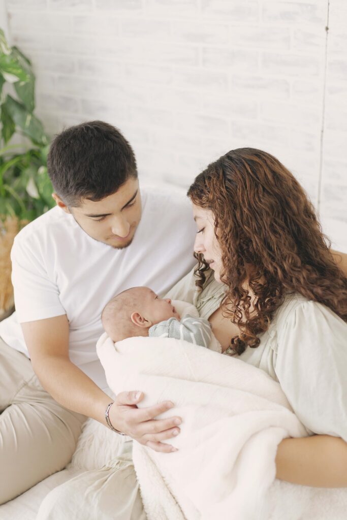 mom and dad posing for newborn photos with baby