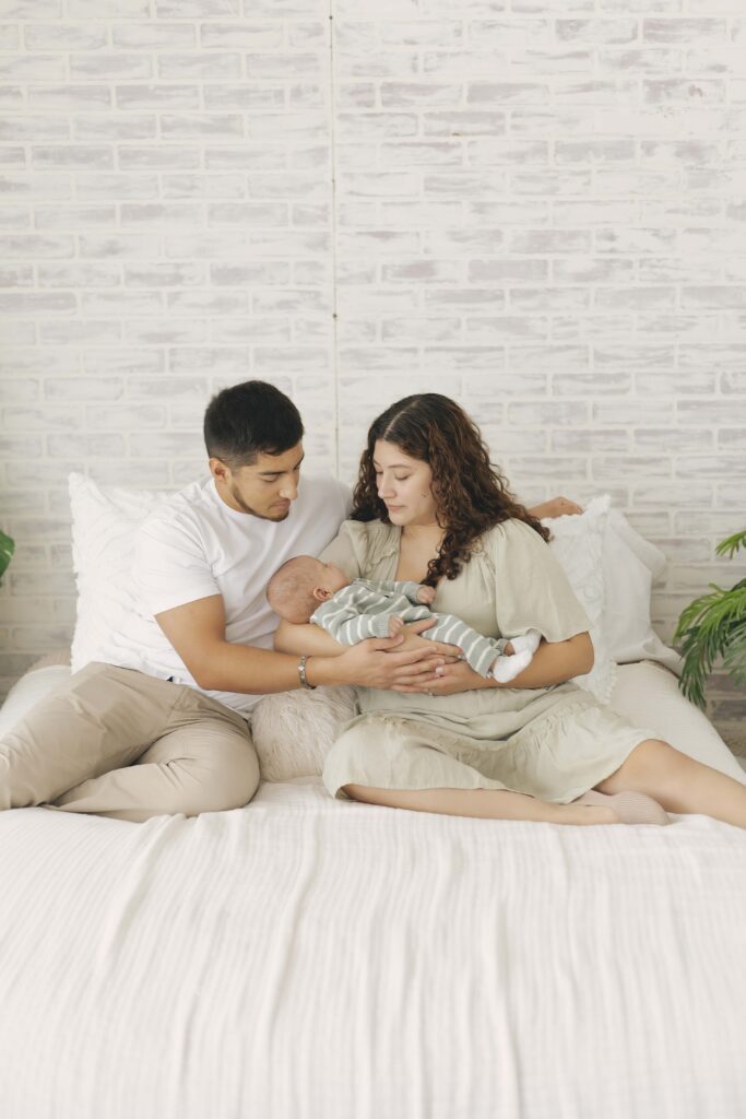 mom and dad posing for newborn photos with baby