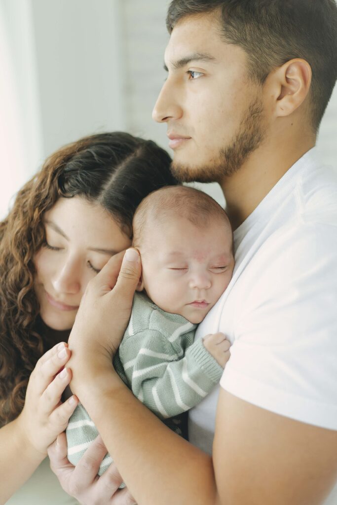 mom and dad posing for newborn photos with baby