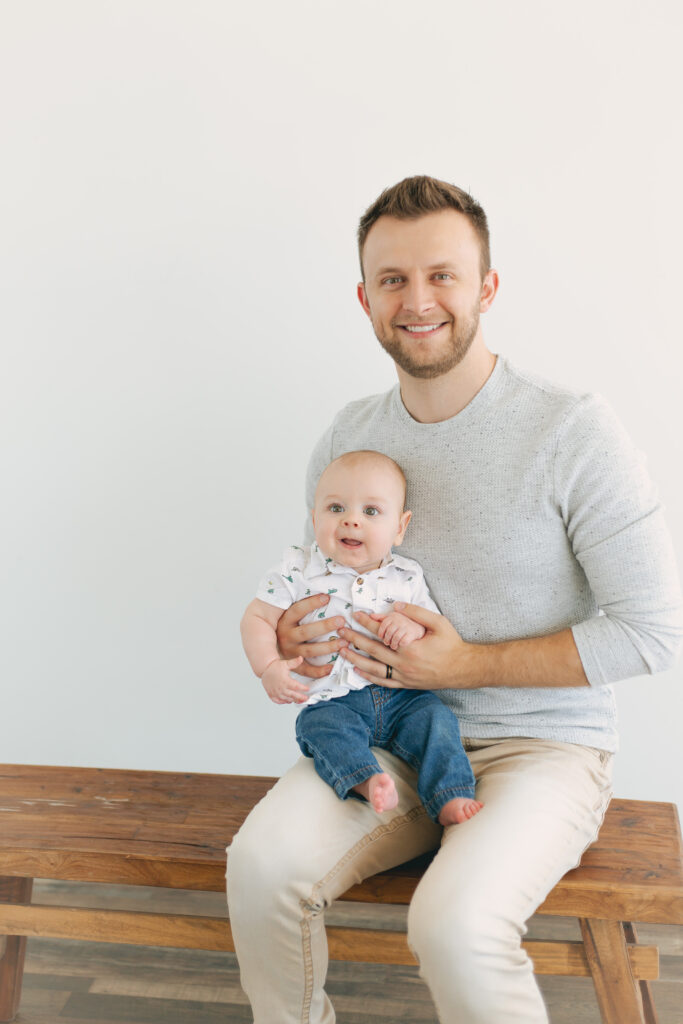 dad holding baby posing for photos showcasing dad's outfit 