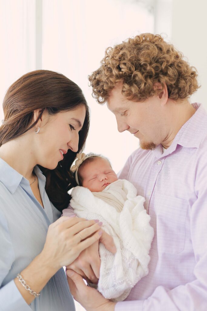 mom and dad posing with their newborn for their newborn photo showcasing dad's outfit 