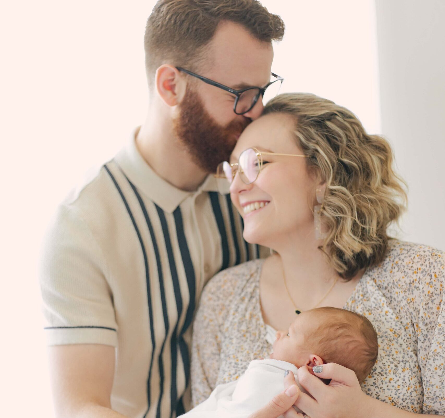mom and dad posing with their newborn for their newborn photo showcasing dad's outfit