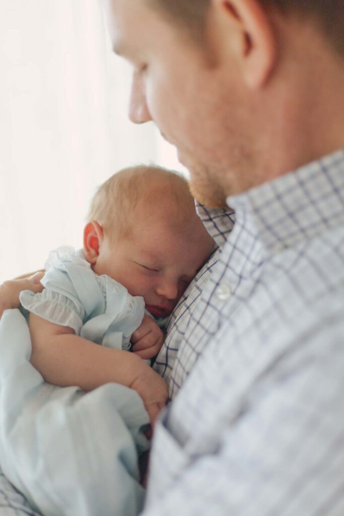 dad holding newborn baby posing for their  newborn session showcasing dad's outfit 